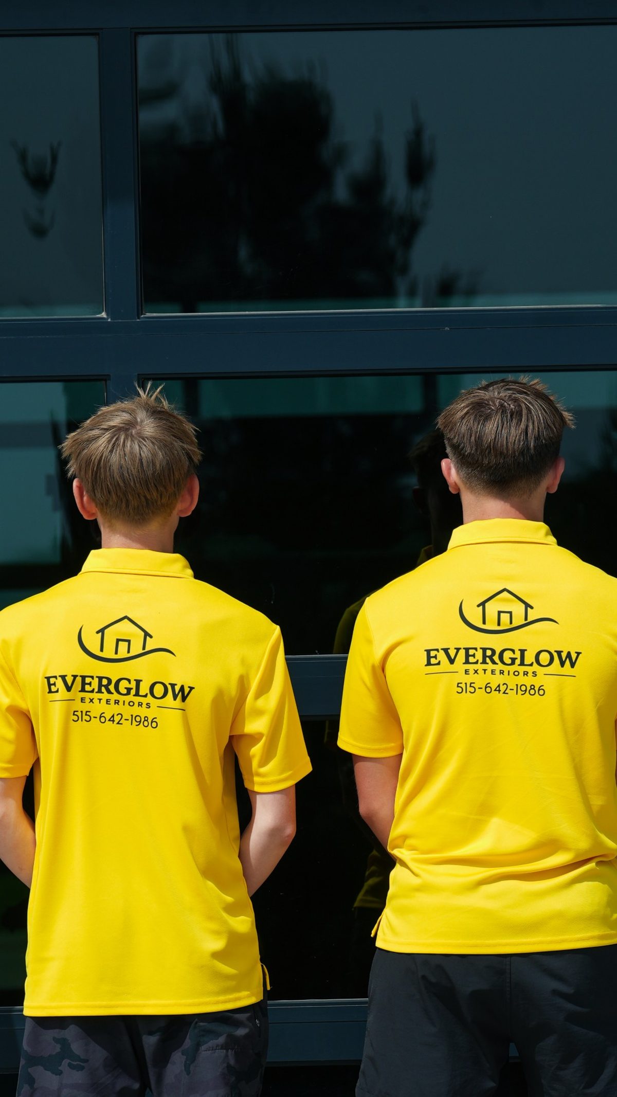 Two EverGlow Exteriors crew members from behind, facing a glass storefront